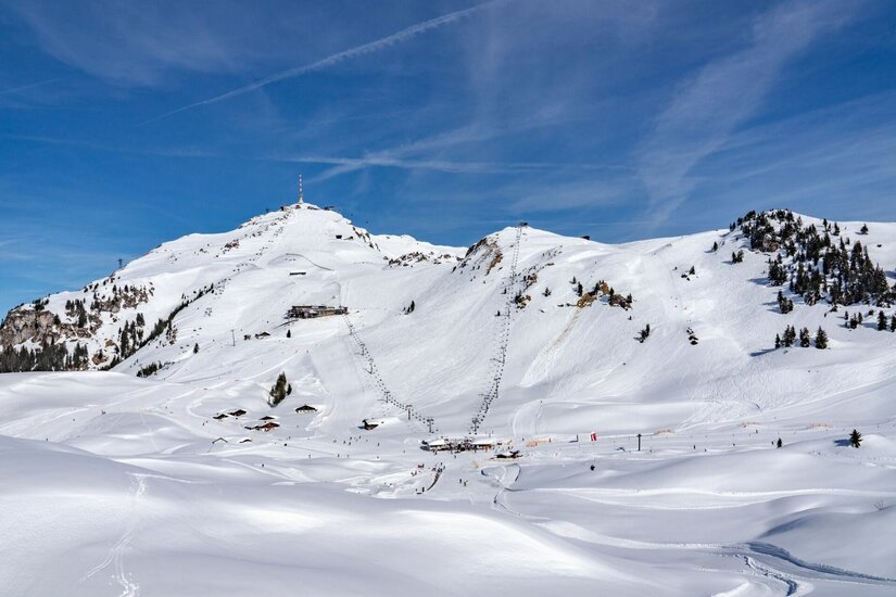 Winterlandschaft Kitzbüheler Horn Verschneites Skigebiet am Kitzbüheler Horn mit Liftanlagen und Skipisten unter blauem Himmel.