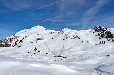 Verschneites Skigebiet am Kitzbüheler Horn mit Liftanlagen und Skipisten unter blauem Himmel.
