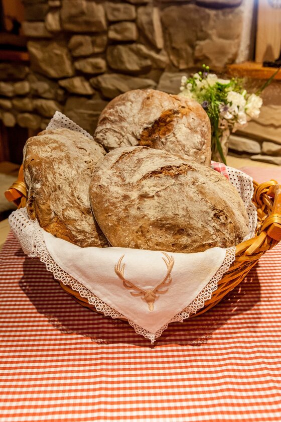 Frisches Bauernbrot im Korb Drei runde Brotlaibe in einem Weidenkorb auf einer rot-weiß karierten Tischdecke.
