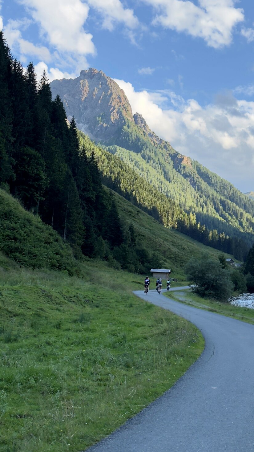 Radfahrer auf der Labalm-Tour Radfahrer auf einer asphaltierten Bergstraße vor bewaldeten Hängen und einem markanten Felsgipfel.