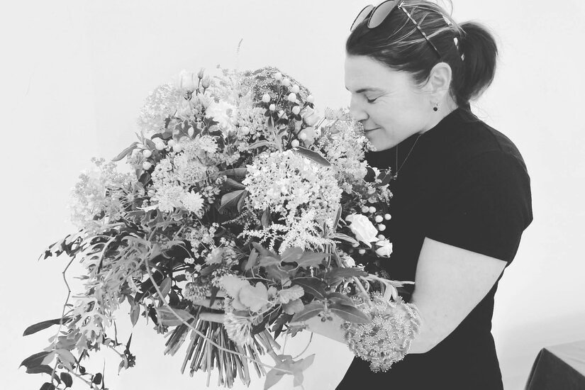Schwarz-Weiß-Aufnahme einer Frau, die an einem großen Blumenstrauß riecht.