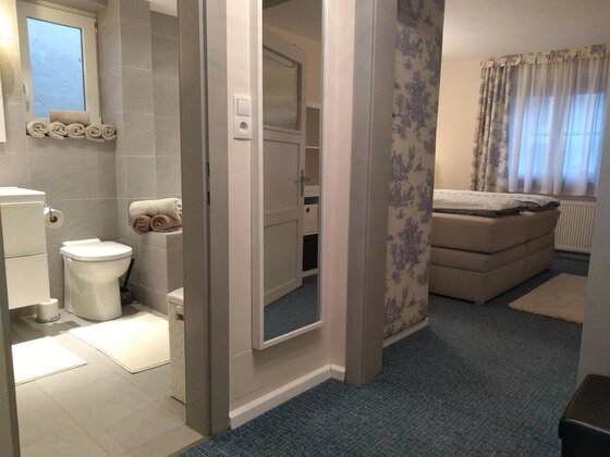 Badezimmer und Schlafzimmer Suite Blick vom Flur in ein gefliestes Badezimmer mit WC und ein Schlafzimmer mit Doppelbett.
