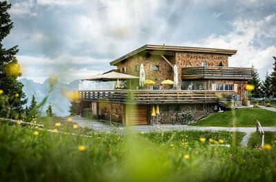 Berghaus Tirol im Sommer Modernes Berghaus aus Holz mit großer Terrasse vor Gebirgspanorama.