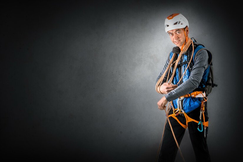 Anton Landmann Ein Kletterer in einer Sicherheitsausrüstung steht mit Seilen in der Hand. Er trägt einen Helm und schaut fokussiert in die Kamera.