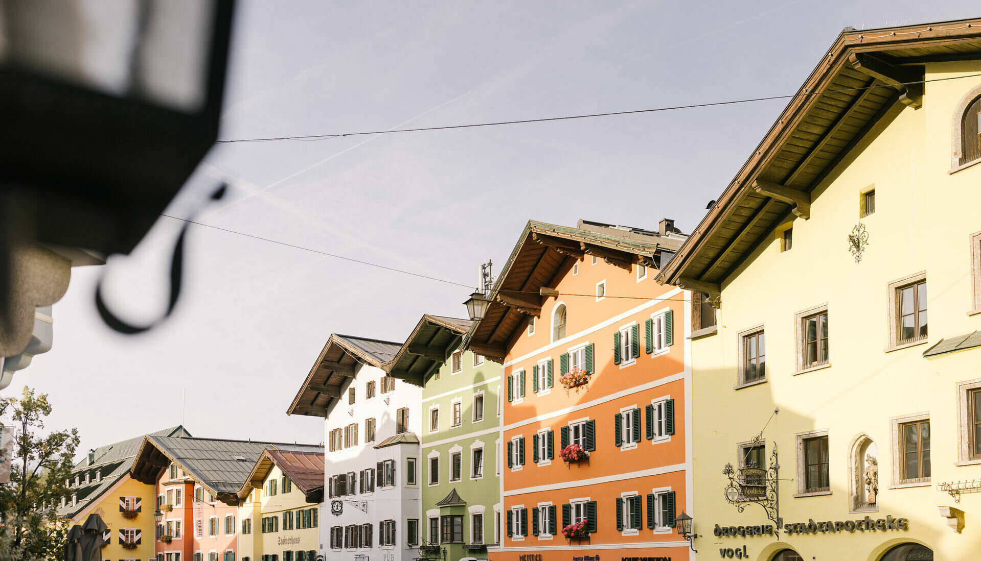 Bunte Fassaden von Gebäuden in einer malerischen Stadt, die im Herbstlicht erstrahlen und eine einladende Atmosphäre schaffen.