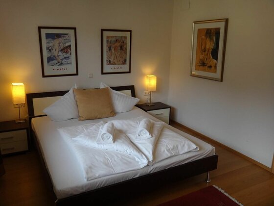 Erstes Schlafzimmer im Penthouse Doppelbett mit weißer Bettwäsche, zwei Nachttischen und Bildern an der Wand.