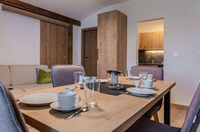 Essbereich Apartment Großvenediger Gedeckter Holztisch mit Geschirr und Gläsern in einem modern eingerichteten Apartment.