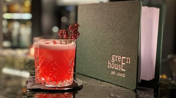 Ein roter Drink an der Bar dekoriert mit Blumen