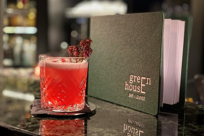 Ein roter Drink an der Bar dekoriert mit Blumen