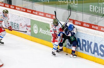 Ein spannendes Eishockeyspiel, in dem zwei Spieler um den Puck kämpfen. Einer der Spieler wird an die Bande gedrängt.