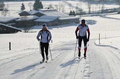 Skilanglauf auf der Sportloipe Zwei Personen beim Skilanglauf auf einer präparierten Loipe in einer verschneiten Landschaft.