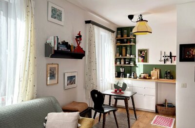 Apartment Alberg und Kathi Ein gemütliches Wohnzimmer mit einer kleinen Essecke und einer Küche im Hintergrund. Helle Farben und eine einladende Atmosphäre prägen den Raum.