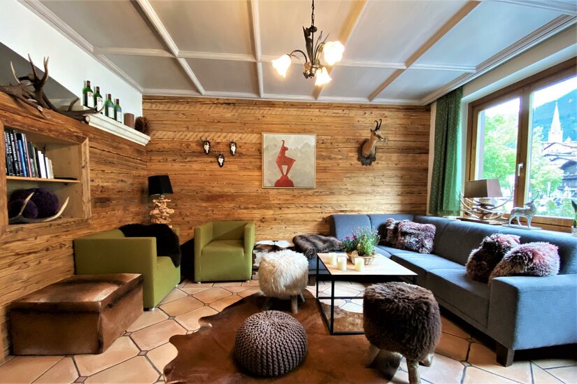 Gams Lounge im Hotel Gamshof Rustikaler Loungebereich mit Holzverkleidung, Sofas, Sesseln und Jagddekor.