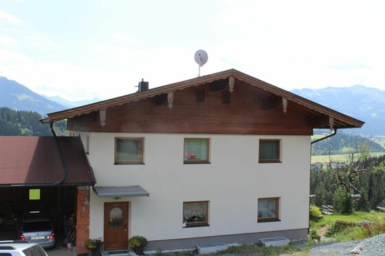 Wohnhaus mit Bergblick Zweistöckiges Wohnhaus mit weißer Fassade und dunklem Holzdach vor einer Bergkulisse.