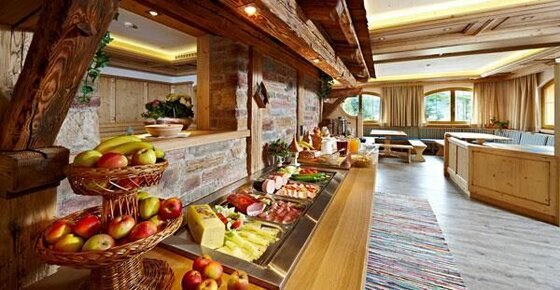 Buffet im Jugendhotel Noichl Frühstücksbuffet mit Obstkörben, Aufschnitt und Käse in einem rustikalen Speisesaal mit Holzelementen.