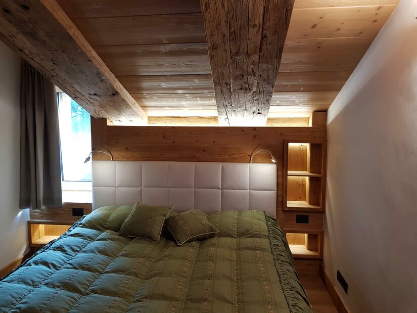 Schlafzimmer Apartment Südberge Doppelbett in einem Zimmer mit Holzdecke und Holzwänden.