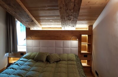 Doppelbett in einem Zimmer mit Holzdecke und Holzwänden.