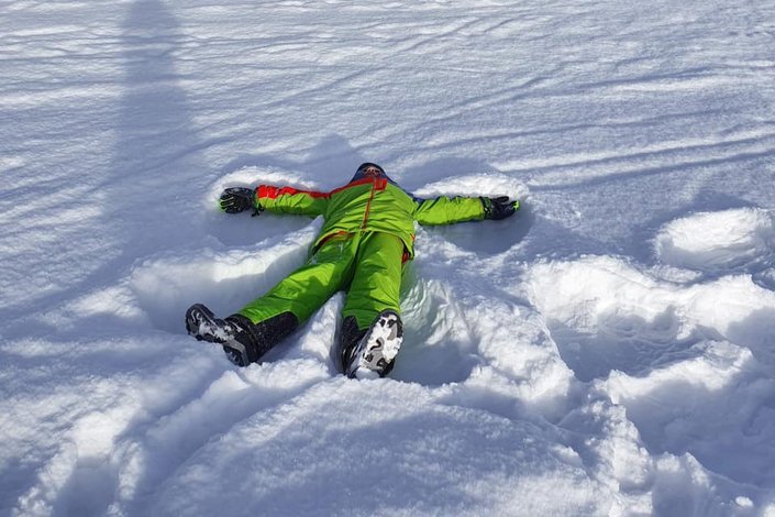 Kind beim Schneeengel machen 