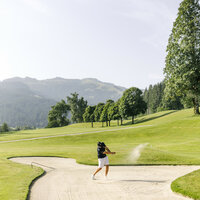 A golfer plays the ball out of a bunker
