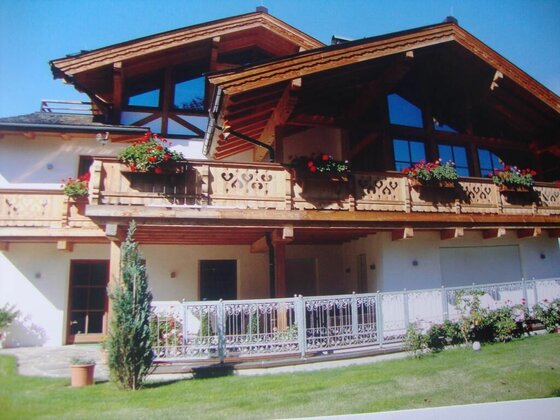 Haus Andreas Kitzbühel Sommer Alpines Holzhaus mit Blumenbalkon und Garten.