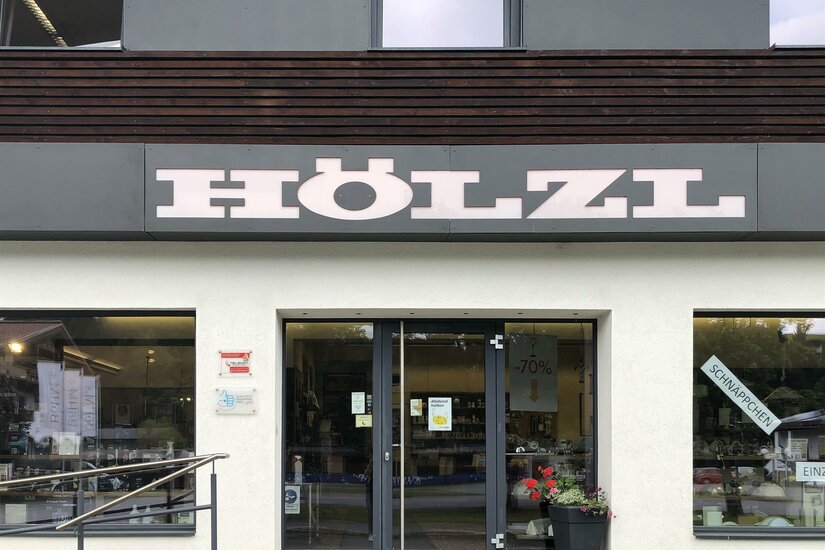 Ein Geschäft mit dem Namen "HÖLZL". Die Eingangstür ist einladend und hat große Fenster.