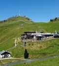 Berghaus und Seilbahnstation am Kitzbüheler Horn mit Sendeturm im Hintergrund.