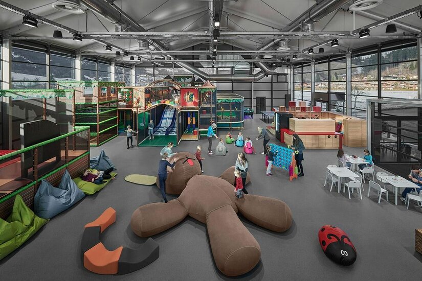 Lisi World Indoor-Spielplatz Großer Indoor-Spielplatz mit Klettergerüsten, Rutschen und Sitzsäcken in einer modernen Halle.