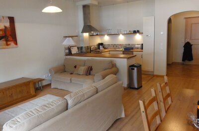 Wohnbereich mit beigen Sofas und offener Küchenzeile in einer Ferienwohnung.
