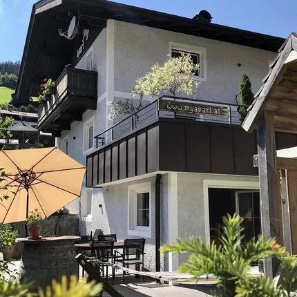 Ein stilvolles Gebäude mit einem Balkon und einer Terrasse, umgeben von Pflanzen und einer ruhigen, grünen Umgebung.