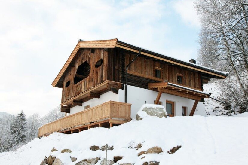 Ansicht 2 Ein charmantes Holzhaus in einer schneebedeckten Landschaft. Die Umgebung ist ruhig und malerisch, umgeben von Bäumen.
