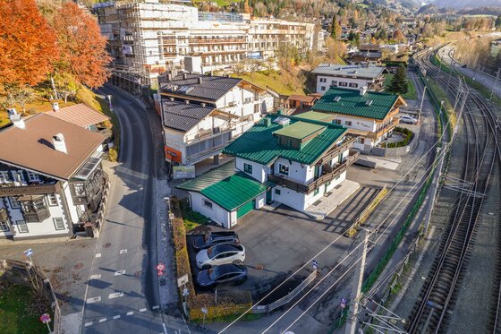 Umgebung NA-Home Kitzbühel Luftaufnahme von Wohnhäusern neben einer Bahnstrecke und einer Straße in Kitzbühel.