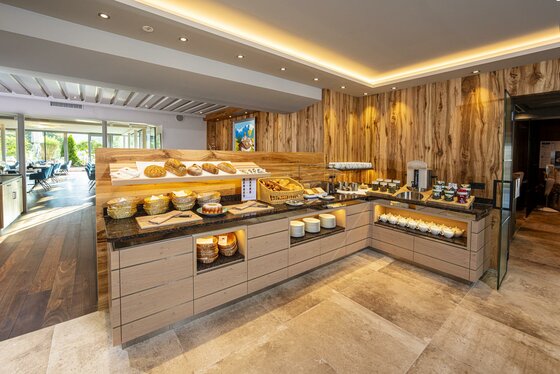 ©MartinRaffeiner_07_2024_RF_5081 Ein einladendes Frühstücksbuffet mit frischen Lebensmitteln und Getränken. Der Raum hat eine moderne und gemütliche Atmosphäre.
