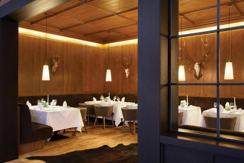 Fondue Stube im Restaurant Steinberg Rustikale Gaststube mit holzgetäfelten Wänden, eingedeckten Tischen und Jagdtrophäen.