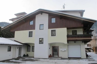 Mehrstöckiges Landhaus mit Holzfassade im Giebelbereich und verschneitem Vorplatz.