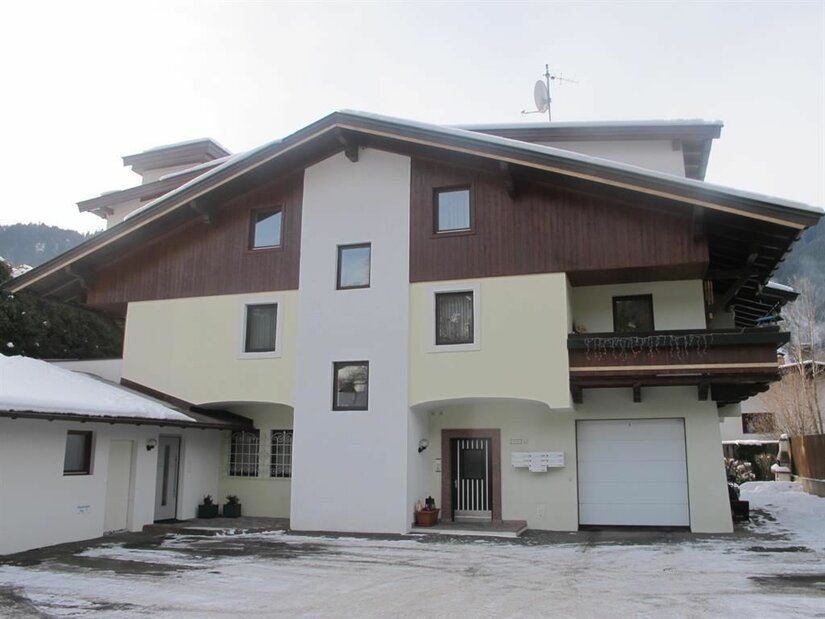 Mehrstöckiges Landhaus mit Holzfassade im Giebelbereich und verschneitem Vorplatz.