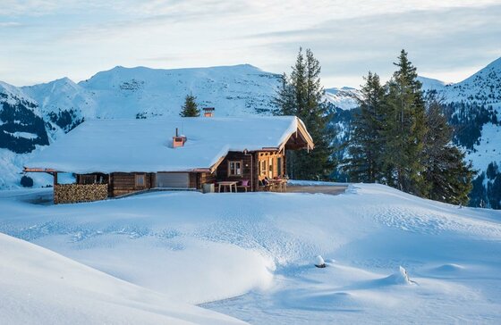 Wirts´Hochalm im Winter Schneebedeckte Holzhütte in einer alpinen Winterlandschaft mit Bergen im Hintergrund.