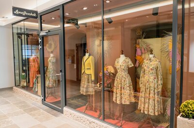 Lena Hoschek Passage 3 Schaufenster mit Kleidern auf Mannequins hinter einer Glasfront.
