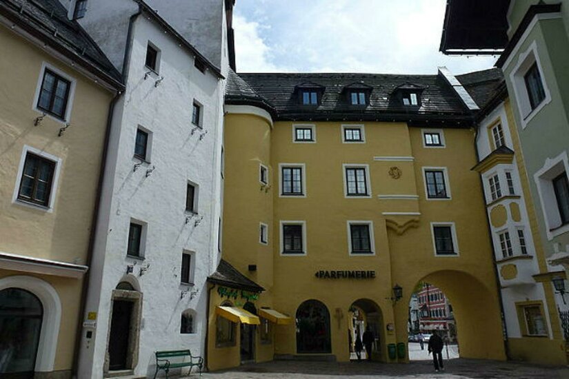 Pfleghof Ein malerischer Platz mit bunten Gebäuden und einem gelben Haus mit einem Tor. Die Architektur zeigt einen typischen, charmanten Stil.
