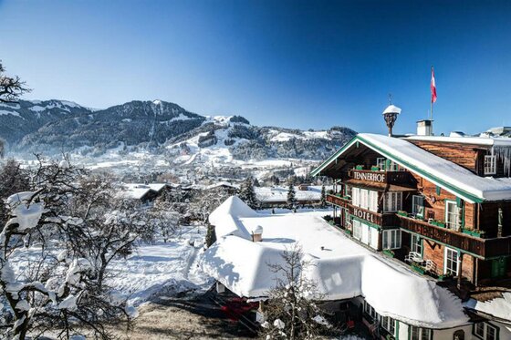 Tennerhof im Winter Verschneites Hotel Tennerhof in alpiner Landschaft mit Blick auf Kitzbühel und die Berge bei blauem Himmel.