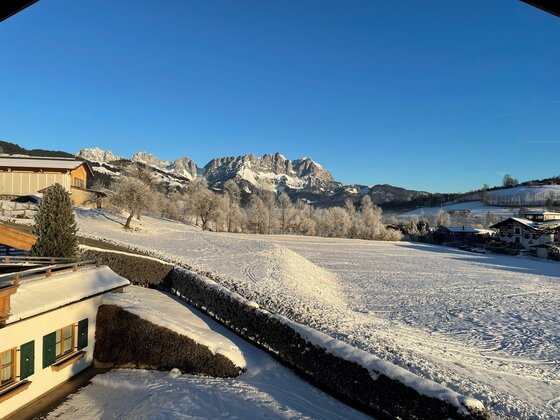Aussicht Wilder Kaiser Verschneite Wiese mit Blick auf das Gebirgsmassiv des Wilden Kaisers unter blauem Himmel.