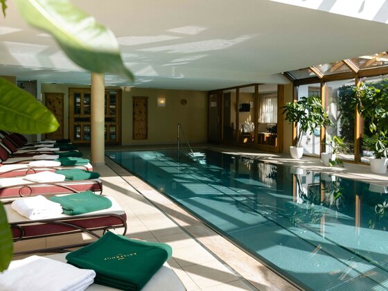 Indoor-Pool im Hotel Kaiserhof Hallenbad mit Edelstahlbecken, Liegestühlen und großen Fensterfronten.