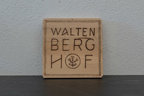 _22A3363-HDR Ein aus Holz gefertigtes Schild mit der Aufschrift „Walten Berg Hof“. Es zeigt eine einfache, rustikale Gestaltung.