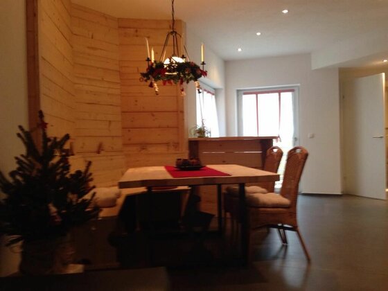 Haus Haas Essgruppe Moderner Essbereich mit Holztisch, Rattanstühlen und holzverkleideter Wand.