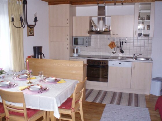 Küchenzeile im Apartment Moderne Küchenzeile aus hellem Holz mit angrenzendem Esstisch und Stühlen.