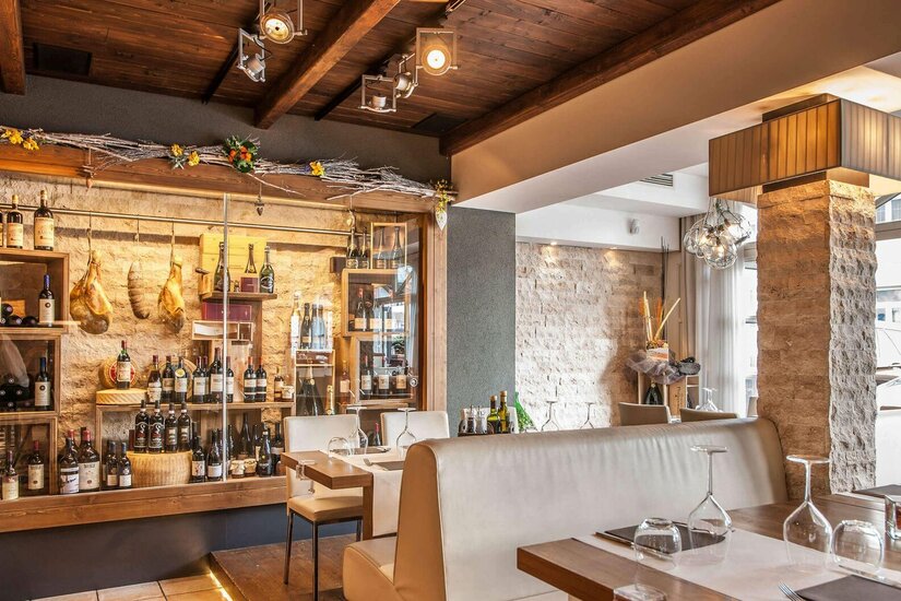 Restaurant Hostaria Innenraum Innenansicht eines Restaurants mit Weinfächern, Steinsäule und eingedeckten Tischen.