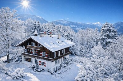 Winter Sonne Ein charmantes Holzhaus in einer verschneiten Landschaft. Die Bäume und der Himmel sind klar und strahlend.