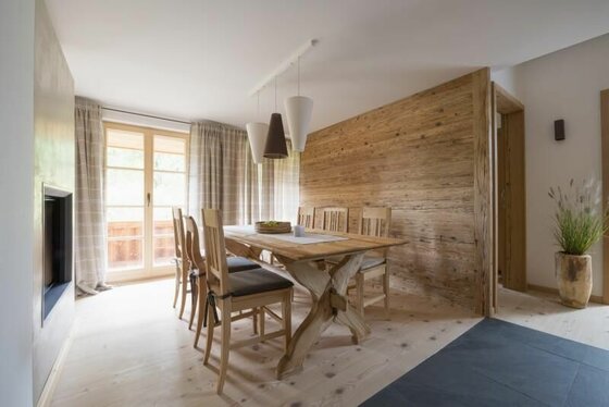 Esstisch Hahnenkamm Moderner Essbereich mit Holztisch, Stühlen und einer Wandverkleidung aus Altholz.