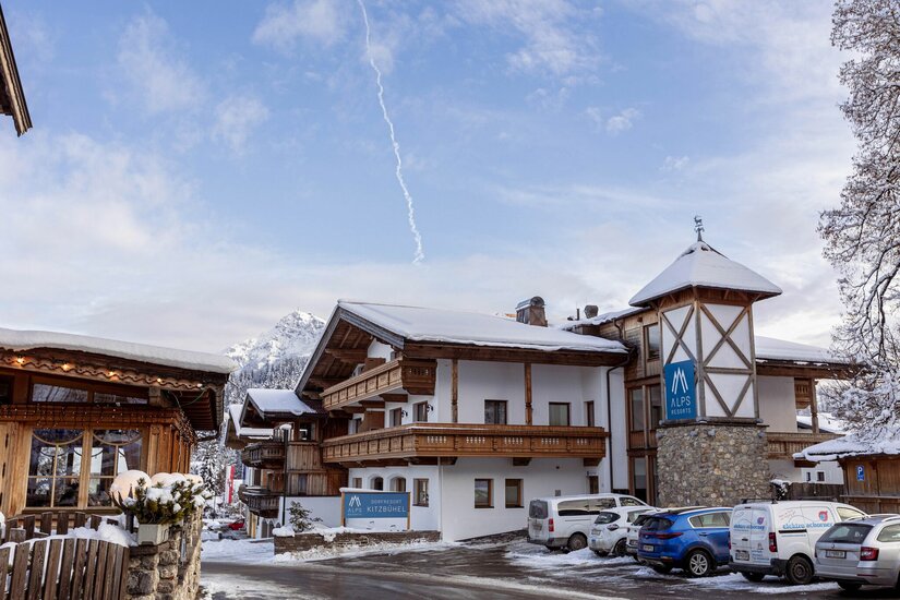 Dorfresort Kitzbühel Außenansicht Außenansicht des Dorfresort Kitzbühel mit schneebedeckten Dächern und Parkplatz vor dem Gebäude.