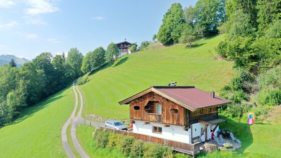 IMG-20230823-WA0033 Ein hübsches Holzhaus inmitten grüner Wiesen und Bäume. Der Himmel ist blau und die Landschaft ist ruhig und malerisch.