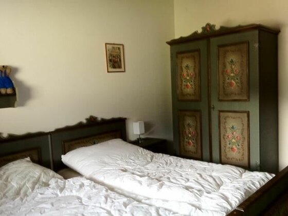 Schlafzimmer mit rustikalem Doppelbett und bemaltem Bauernschrank aus Holz.